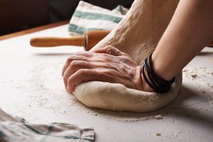 Mains qui pétrissent de la pâte à pain